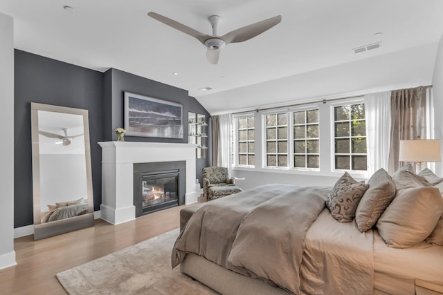 7 Honeysuckle Ln, Rye Brook, NY 10573 - bedroom with wood finished floors, a glass covered fireplace, vaulted ceiling, and ceiling fan