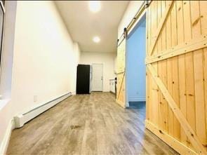130 W 165th St, Bronx, NY 10452 - hall with a barn door, a baseboard heating unit, recessed lighting, and wood finished floors