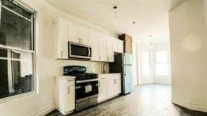 130 W 165th St, Bronx, NY 10452 - kitchen featuring stainless steel appliances, white cabinets, light countertops, and wood finished floors
