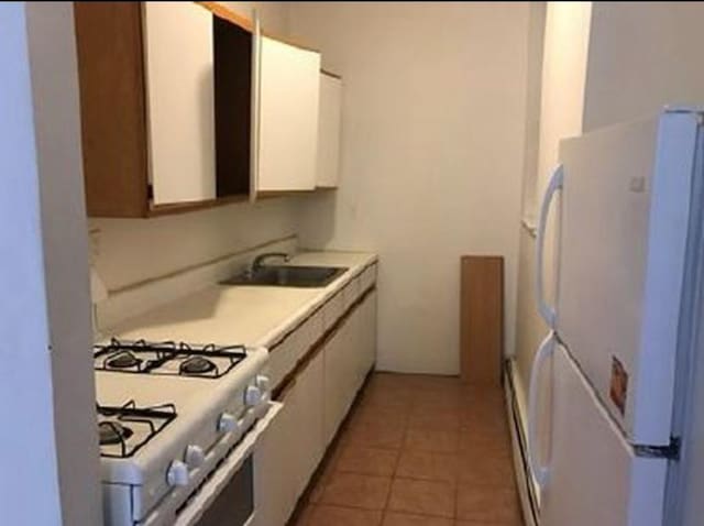 1047 Faile St Unit 1047A, Bronx, NY 10459 - kitchen with white appliances, white cabinets, light countertops, and light tile patterned flooring
