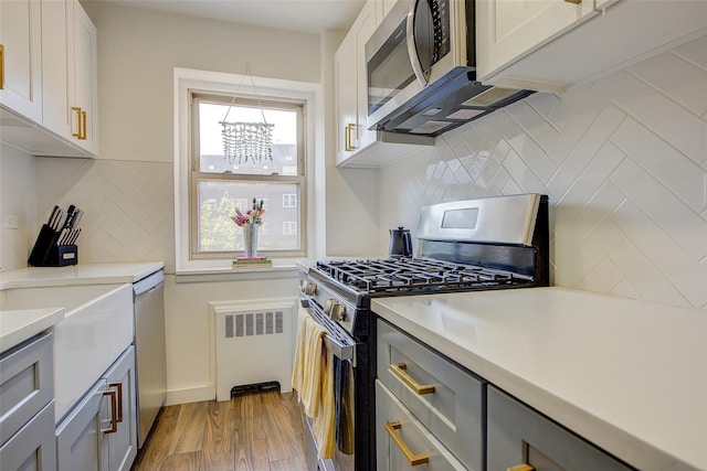 144-60 Gravett Rd Unit 4J, Kew Garden Hills, NY 11367 - kitchen featuring appliances with stainless steel finishes, radiator, decorative backsplash, and gray cabinetry