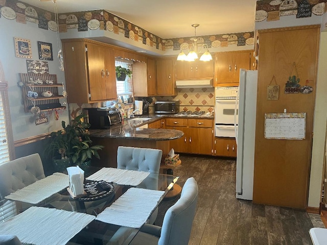 15916 92nd St, Howard Beach, NY 11414 - kitchen featuring white appliances, under cabinet range hood, brown cabinetry, a peninsula, and a warming drawer