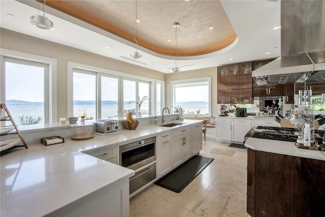 74 River Rd, Nyack, NY 10960 - kitchen with island range hood, a tray ceiling, stainless steel microwave, a warming drawer, and light stone counters