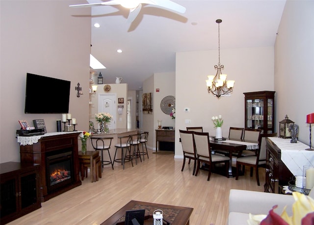 507 Constance Ln, Port Jefferson Station, NY 11776 - living room with light wood-style floors, a ceiling fan, a chandelier, a glass covered fireplace, and high vaulted ceiling
