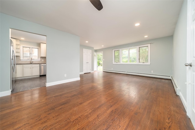 7 Miller Dr, Lake Grove, NY 11755 - unfurnished living room with a baseboard heating unit, dark wood-type flooring, a ceiling fan, and recessed lighting