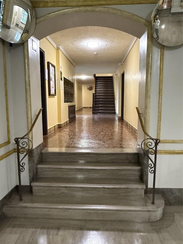 61-41 Saunders St Unit B44, Rego Park, NY 11374 - stairs featuring arched walkways, crown molding, a textured ceiling, and wood finished floors