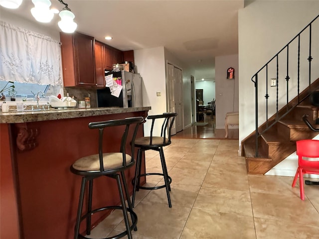616 Port Richmond Ave, Staten Island, NY 10302 - kitchen featuring stainless steel fridge, dark countertops, a kitchen bar, light tile patterned floors, and decorative backsplash