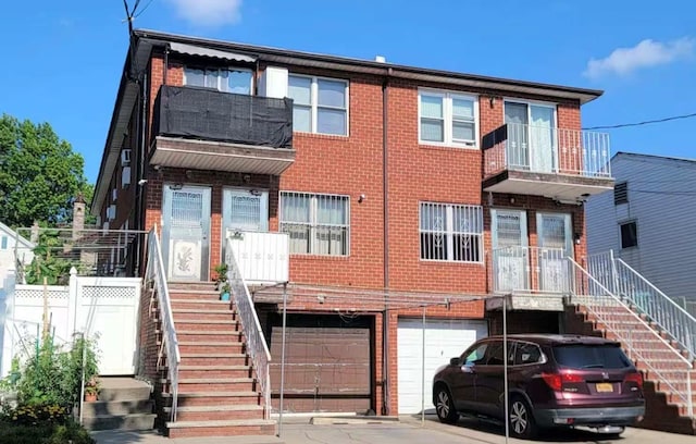 20-45 120th St, College Point, NY 11356 - view of front of house with stairway, an attached garage, brick siding, and driveway