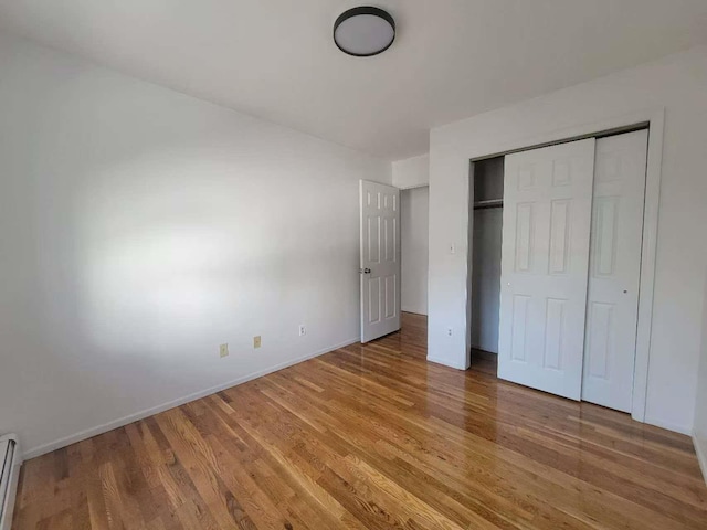 20-45 120th St, College Point, NY 11356 - unfurnished bedroom with light wood finished floors, baseboard heating, and a closet