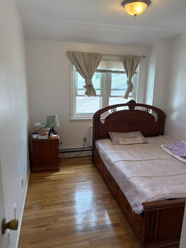 20-45 120th St, College Point, NY 11356 - bedroom featuring a baseboard heating unit and light wood-style floors