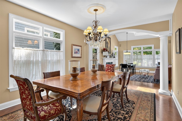 48 Fieldstone Ln, Oyster Bay, NY 11771 - dining space featuring arched walkways, decorative columns, wood finished floors, a chandelier, and vaulted ceiling
