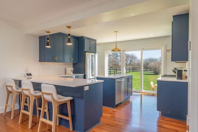 1030 Horseshoe Dr, Cutchogue, NY 11935 - kitchen featuring blue cabinets, stainless steel appliances, a peninsula, a kitchen island, and light countertops