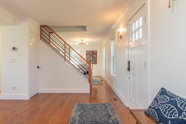 1030 Horseshoe Dr, Cutchogue, NY 11935 - foyer entrance featuring light wood finished floors, ornamental molding, stairway, and a chandelier