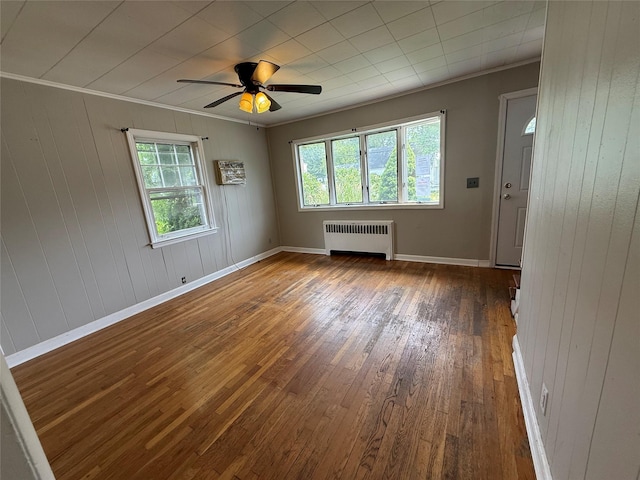449 N Indiana Ave, Lindenhurst, NY 11757 - unfurnished room featuring radiator, wood-type flooring, healthy amount of natural light, ceiling fan, and wooden walls
