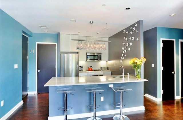 180 Woodpoint Rd Unit 1R, Brooklyn, NY 11211 - kitchen featuring appliances with stainless steel finishes, dark wood-style flooring, white cabinets, backsplash, and a kitchen breakfast bar