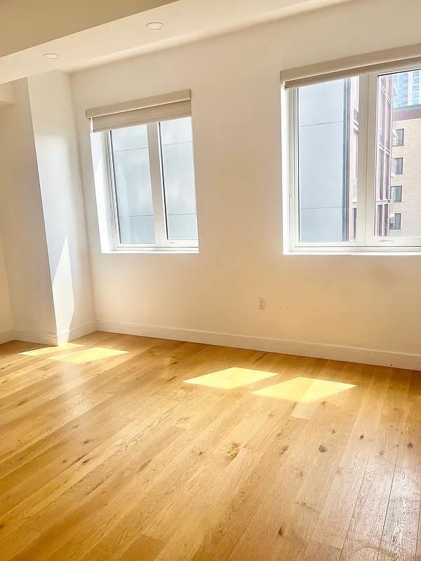 24-16 Queens Plz S Unit 4J, Long Island City, NY 11101 - empty room featuring baseboards and light wood-style floors