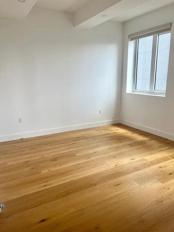 24-16 Queens Plz S Unit 4J, Long Island City, NY 11101 - spare room featuring baseboards and light wood finished floors