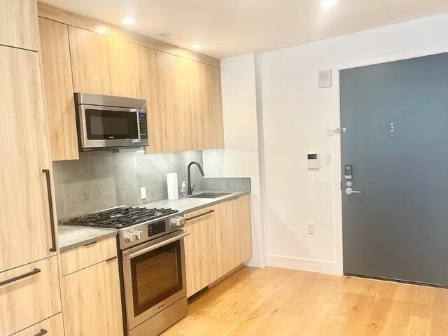 24-16 Queens Plz S Unit 4J, Long Island City, NY 11101 - kitchen featuring light brown cabinets, modern cabinets, stainless steel appliances, light wood-type flooring, and recessed lighting