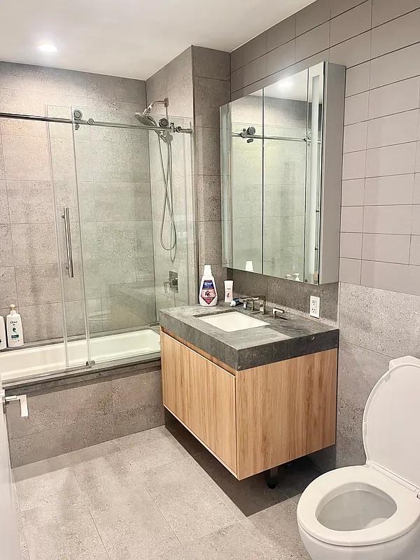 24-16 Queens Plz S Unit 4J, Long Island City, NY 11101 - full bath featuring tiled shower / bath combo, vanity, and tile walls