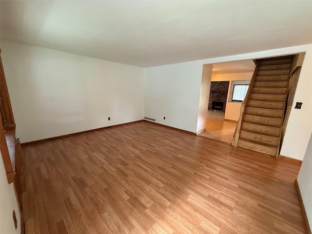 719 Greenbelt Pkwy W, Holbrook, NY 11741 - spare room featuring light wood-style floors, stairway, and a large fireplace