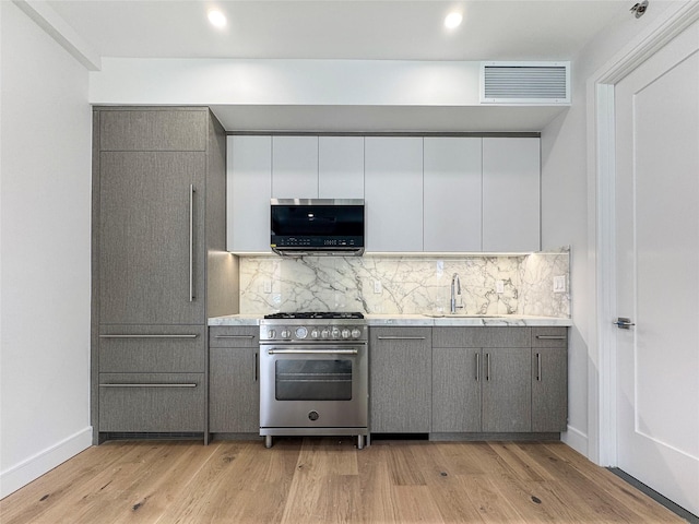 21-31 Shore Blvd Unit 1G, Astoria, NY 11105 - kitchen with appliances with stainless steel finishes, gray cabinetry, tasteful backsplash, light wood-style flooring, and recessed lighting