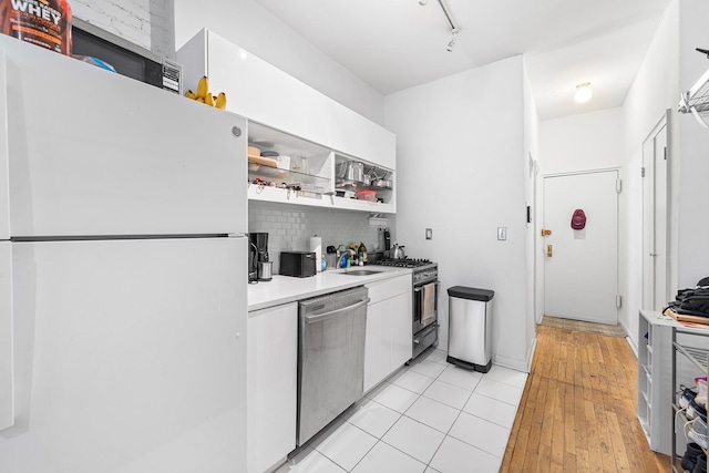 313 E 89th St Unit 2C, New York Manhattan, NY 10128 - kitchen featuring appliances with stainless steel finishes, white cabinets, open shelves, backsplash, and track lighting