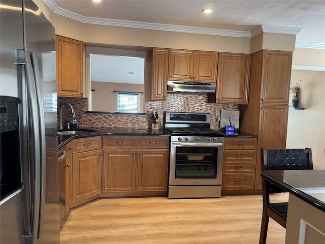3805 Mansfield Dr, Seaford, NY 11783 - kitchen with stainless steel appliances, under cabinet range hood, brown cabinetry, light wood-style flooring, and ornamental molding