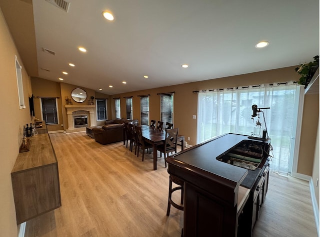 3805 Mansfield Dr, Seaford, NY 11783 - dining room with light wood-type flooring, recessed lighting, lofted ceiling, and a glass covered fireplace