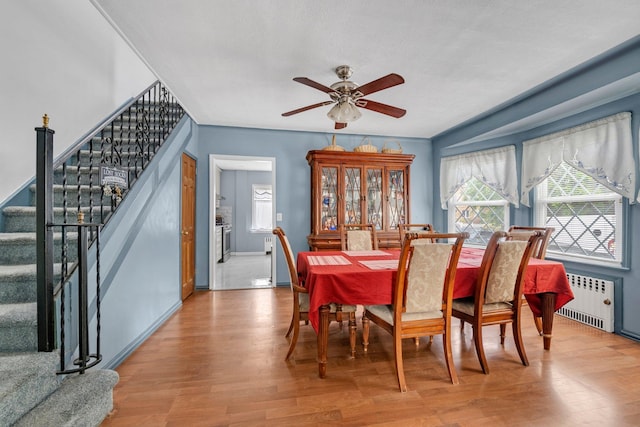 7609 79th St, Glendale, NY 11385 - dining space with radiator, wood finished floors, ceiling fan, and stairway