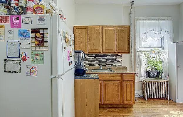 1304 Pacific St Unit B1, Brooklyn, NY 11216 - kitchen with freestanding refrigerator, backsplash, light wood-type flooring, and brown cabinets