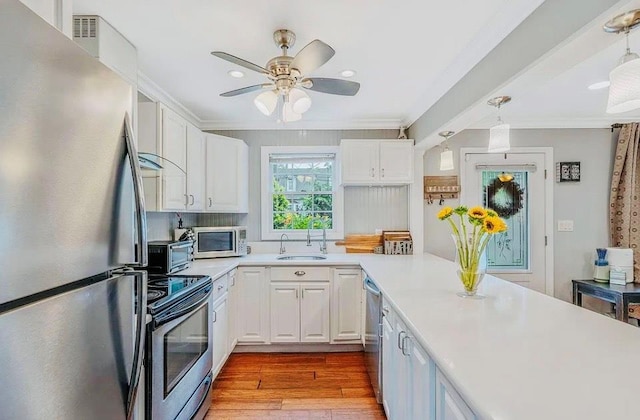24 Lowerre St, Babylon, NY 11702 - kitchen with appliances with stainless steel finishes, wood finished floors, crown molding, white cabinetry, and a ceiling fan
