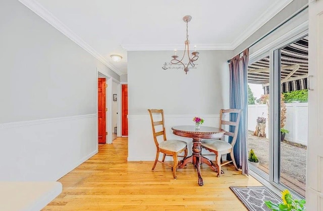 24 Lowerre St, Babylon, NY 11702 - dining space with crown molding, light wood-type flooring, and a chandelier