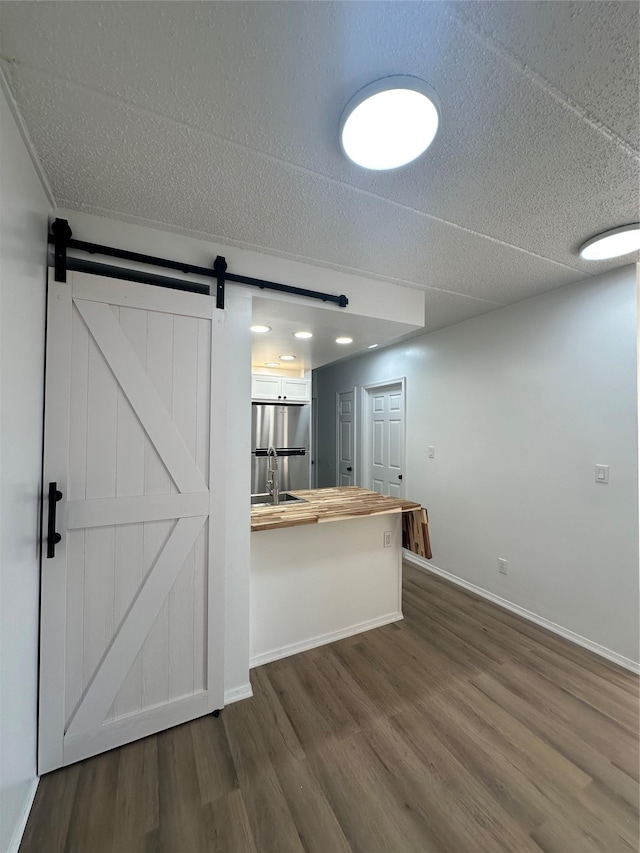 41-28 71st St Unit 4D, Woodside, NY 11377 - kitchen with butcher block countertops, dark wood-type flooring, a barn door, a textured ceiling, and a peninsula