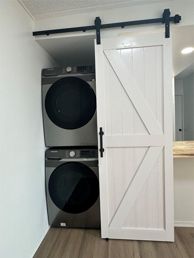 41-28 71st St Unit 4D, Woodside, NY 11377 - laundry area featuring a barn door, stacked washer / dryer, wood finished floors, and a textured ceiling