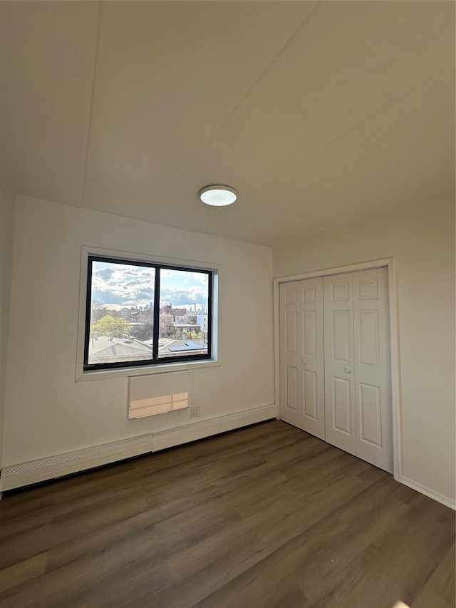41-28 71st St Unit 4D, Woodside, NY 11377 - unfurnished bedroom with dark wood-style floors, a closet, and a baseboard radiator