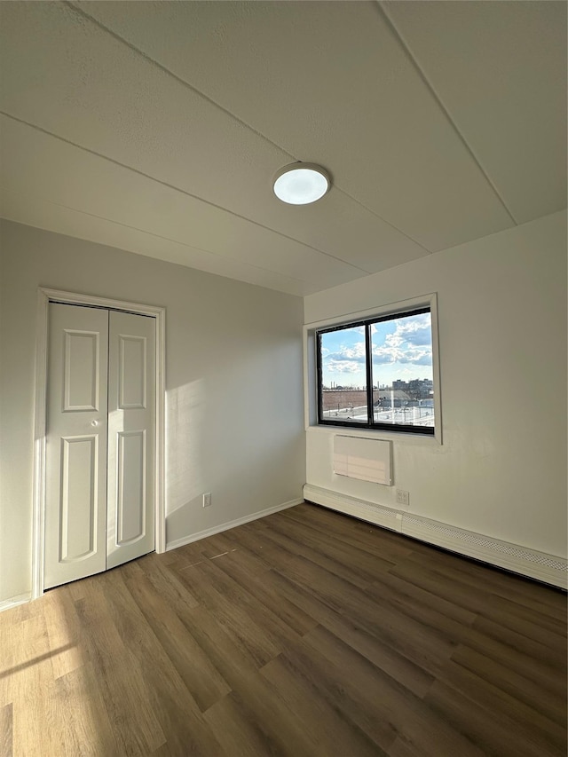 41-28 71st St Unit 4D, Woodside, NY 11377 - unfurnished bedroom with dark wood finished floors, a baseboard radiator, and a closet