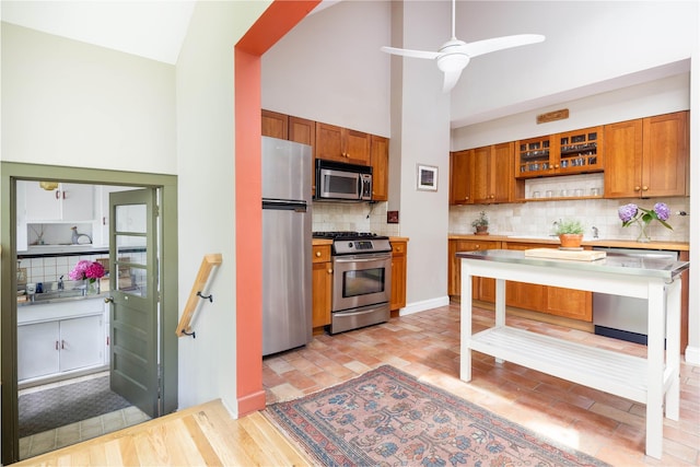 2860 Pine Tree Rd, Cutchogue, NY 11935 - kitchen with stainless steel appliances, brown cabinetry, decorative backsplash, high vaulted ceiling, and light countertops