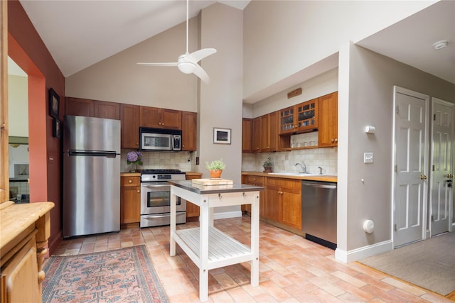 2860 Pine Tree Rd, Cutchogue, NY 11935 - kitchen with stainless steel appliances, brown cabinetry, ceiling fan, backsplash, and high vaulted ceiling