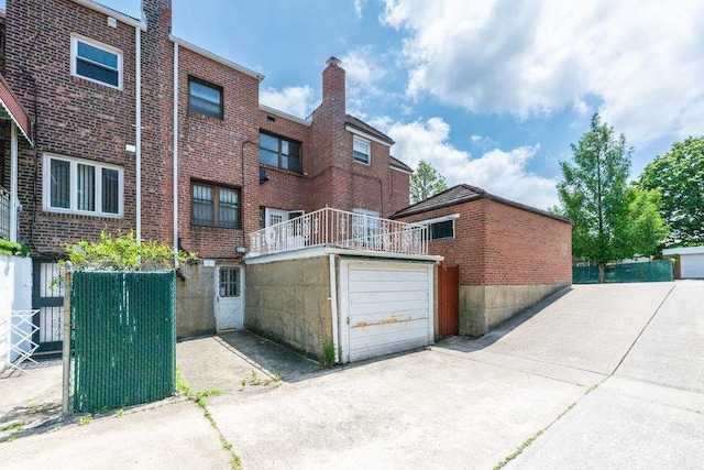 70-40 Utopia Pkwy, Fresh Meadows, NY 11365 - rear view of house with a chimney, brick siding, a garage, and driveway