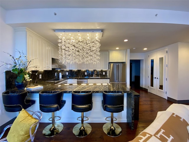 4260 Crescent St Unit 10C, Long Island City, NY 11101 - kitchen with a peninsula, appliances with stainless steel finishes, white cabinetry, dark wood-type flooring, and backsplash