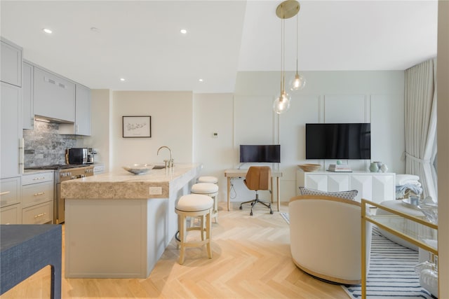 250 E 21st St Unit 9D, New York Manhattan, NY 10010 - kitchen with stainless steel gas range, tasteful backsplash, a kitchen bar, hanging light fixtures, and a kitchen island with sink