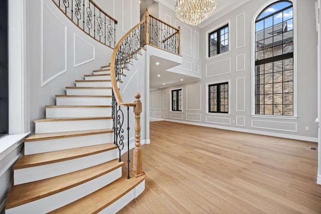 35-26 221st St, Bayside, NY 11361 - stairway featuring a chandelier, wood finished floors, ornamental molding, a decorative wall, and a towering ceiling