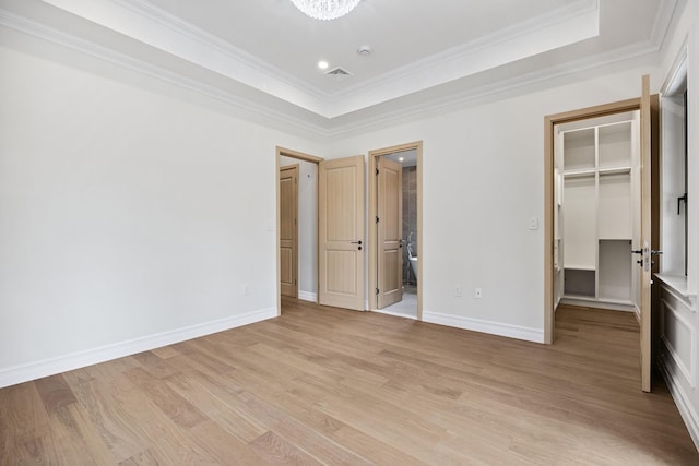 35-26 221st St, Bayside, NY 11361 - unfurnished bedroom with a spacious closet, a tray ceiling, light wood-type flooring, and crown molding