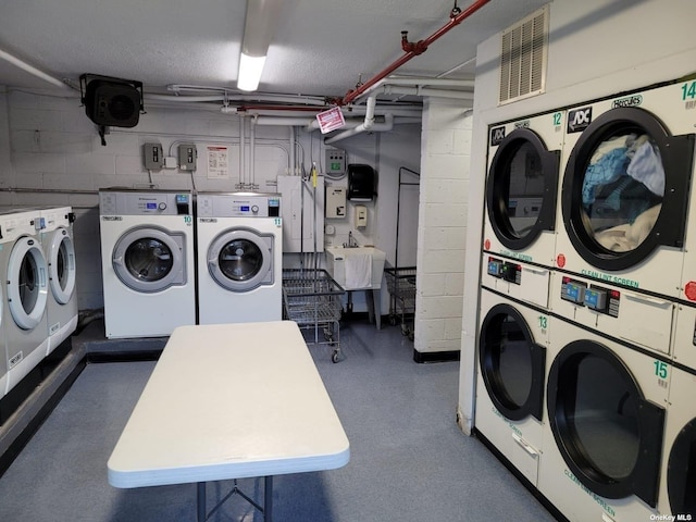 118-17 Union Tpke Unit 14E, Forest Hills, NY 11375 - community laundry with independent washer and dryer, stacked washing machine and dryer, and concrete block wall