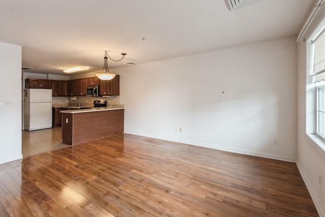 117 Willow Ln, Valley Stream, NY 11580 - kitchen with freestanding refrigerator, light wood-style floors, open floor plan, light countertops, and a peninsula