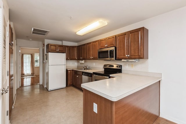 117 Willow Ln, Valley Stream, NY 11580 - kitchen with stainless steel appliances, light countertops, a peninsula, brown cabinets, and light flooring