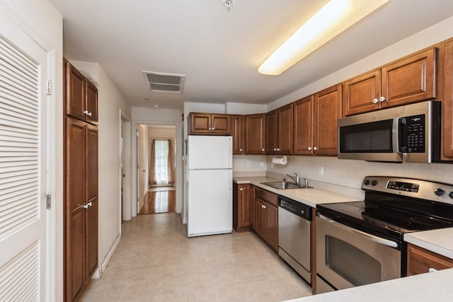 117 Willow Ln, Valley Stream, NY 11580 - kitchen featuring stainless steel appliances, light countertops, and brown cabinetry
