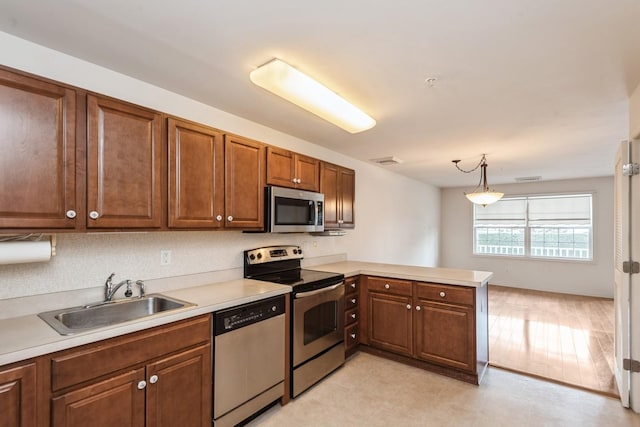 117 Willow Ln, Valley Stream, NY 11580 - kitchen with appliances with stainless steel finishes, a peninsula, light countertops, decorative light fixtures, and brown cabinetry