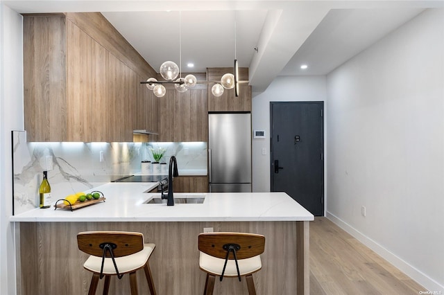14-54 31st Ave Unit 3A, Astoria, NY 11106 - kitchen with modern cabinets, a peninsula, a kitchen bar, stainless steel refrigerator, and light wood-type flooring