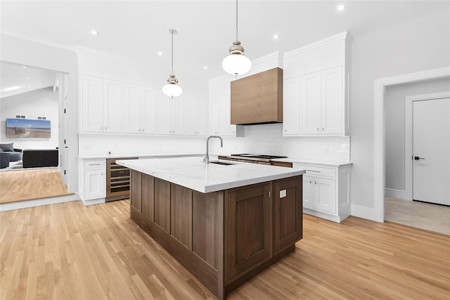 2 Herrick Ln, Southampton, NY 11968 - kitchen with wine cooler, white cabinetry, light wood-style flooring, recessed lighting, and light stone counters
